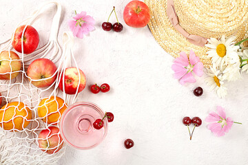 Summer fashion banner on a bright background. Straw hat, fruits in an eco-bag, refreshing alcoholic drinks and chamomile flowers on a sunny table. Vacation and travel concept,
