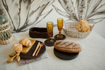 Brown fresh bread and croissants on the trays at the table 