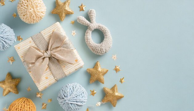 baby accessories concept top view photo of gift box teether knitted bunny rattle toy and stars on isolated pastel blue background with empty space