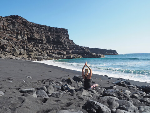 Lanzarote - Frau macht Yoga am schwarzen Strand
