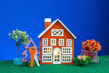 An orange house surrounded by flowers and a Christmas tree with keys on a blue background