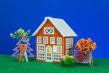 An orange house surrounded by flowers and a Christmas tree with keys on a blue background