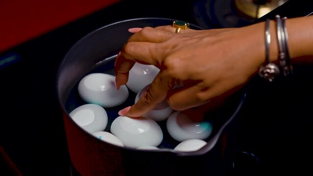 women hand picking up a white egg To drop into a pot for boiled