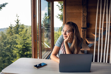 Woman working remotely with laptop in mountain cabin