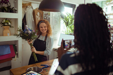 Happy female florist being photographed in her flower shop