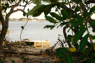 Wide View out to Boca Ciega Bay over a small brown and white rowboat.Beach rocks in front, blue...