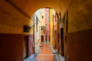 A picturesque narrow alley in a residential district wet with rain in the medieval, colorful old town of Menton, France, along the Cote d'Azur French Riviera.