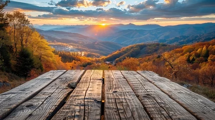 Poster Wooden table top with autumn landscape background at sunset. © amixstudio