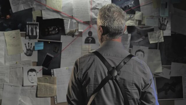 police detective walking in the office examines evidence board while drinking coffee,steadicam shot ,back view of pensive policeman searching proofs about murder case,crime investigation