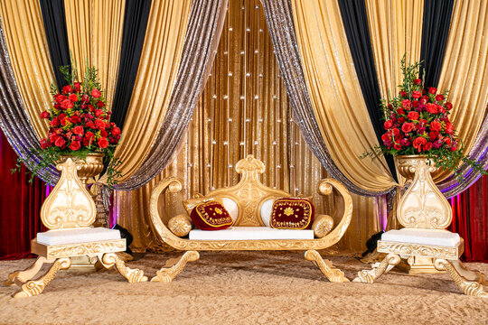 Gold red and ivory Indian wedding stage with rose arrangements