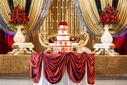 Gold themed Indian wedding stage with tiered wedding cake table