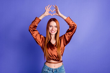 Portrait of nice young woman fingers show heart symbol wear brown shirt isolated on purple color...
