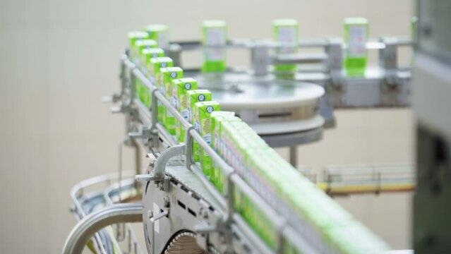 Milk Cartons Traveling along a Conveyor. Production Line. Processing and Pasteurization of Cows Milk. Modern Equipment. Manufacturing of Dairy Based Products. Ready Containers stacking.