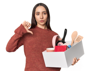 Caucasian young woman holding a box for moving on studio background showing a dislike gesture, thumbs down. Disagreement concept.