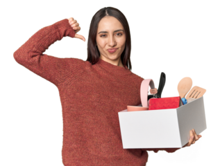 Caucasian young woman holding a box for moving on studio background feels proud and self confident, example to follow.