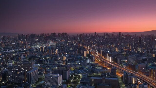 osaka city downtown skyline aerial view timelapse night to day pan,high pov view time lapse of town cityscape,big highway getting into the city center at sunrise