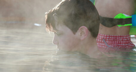 Child inside warm swimming pool water, heated water evaporating