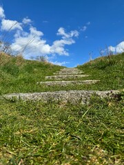 Fototapeta na wymiar stone steps on a green hill against a cloudy sky