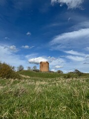 ancient red brick tower on a hill against the background of the sky with clouds