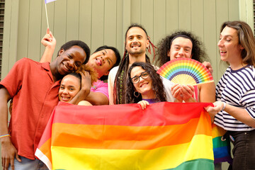 A group of people are holding a rainbow flag and posing for a picture