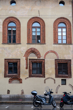 Old house with windows and motor bike on rainy day in Milan, Italy