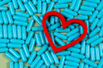 heart shape and blue capsules. Importance of medication treatment