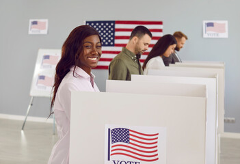 Side view portrait of a happy smiling american voter woman looking cheerful at the camera voting...