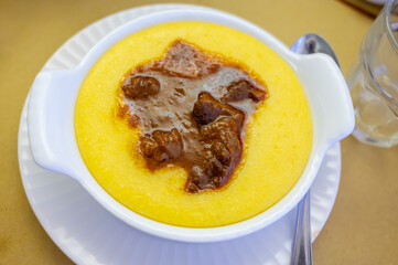 Traditional first course for lunch or dinner in Italy, yellow corn polenta porridge with stew...