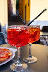 Aperol and Campari Spritz orange bitter long drink cocktails made with liqueur, prosecco sparkling wine, ice cubes and piece of orange, Milan, Italy