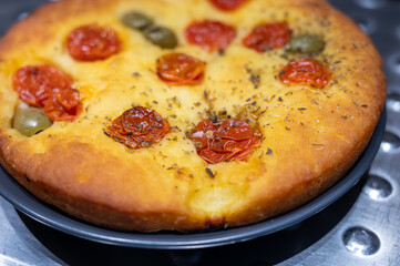 Tasty italian vegetarian food, fresh baked flat foccachia bread with cherry tomatoes, olives and herbs close up