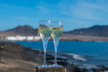 Pouring a glass of champagne on vacation, south of Fuerteventura, Canary islands, blue ocean, mountains