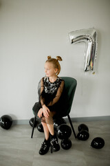 girl in black dress with birthday cake and black balloons 