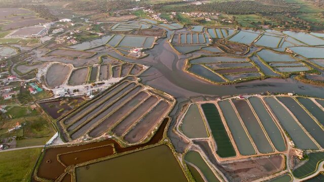 An aerial shot capturing the geometric beauty of fish farm basins bathed in the warm glow of sunset.