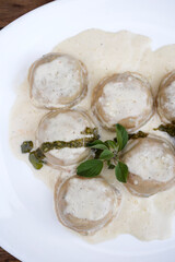 Italian food. Pasta. Top view of mozzarella cheese and ham sorrentinos with cream and pesto sauce,...
