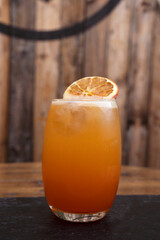 Alcoholic drinks. Closeup view of an orange based tropical cocktail with a rustic wooden background.