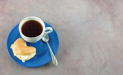 Coffee in white porcelain cup on blue plate with bagel and cream cheese