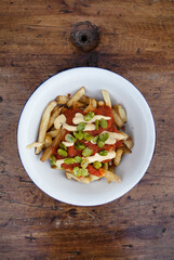 Fried food. Top view of french fries with a spicy sauce and beans, in a white bowl on the table.	

