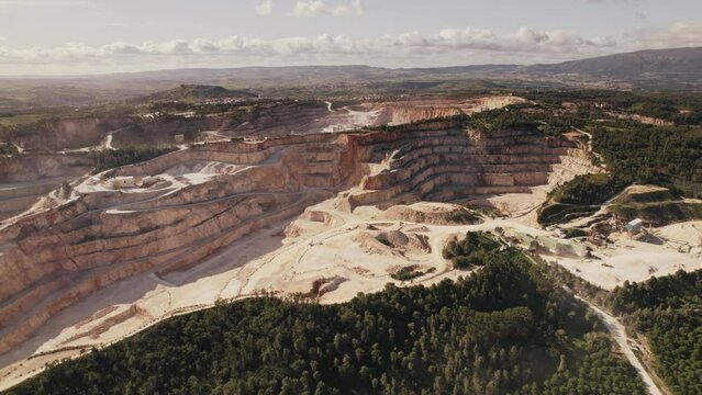 High angle aerial shot capturing the vast and layered terrains of a large quarry surrounded by natural greenery.