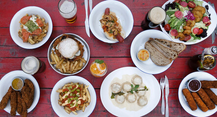 Top view of the restaurant table with drinks and many gourmet dishes such as hamburger, pasta, salad, hot dog, french fries and mozzarella sticks