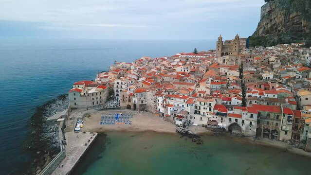 Aerial view of Cefalu, Sicily. Cinematic drone shot of famous travel destination of Italy. Slow drone shot travelling in a wide orbit above the town, view of Cefalu Cathedral and Rocca di Cefalu