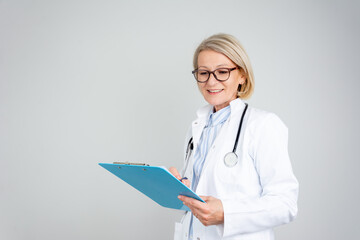 Female doctor holding application form while consulting patient. Smiling female doctor with lab coat isolated holding a clipboard with medical records, writing notes, preparing documents, reports.