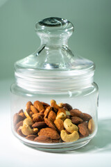 Glass jar filled with a variety of nutrition and healthy snacks and nuts on a white background