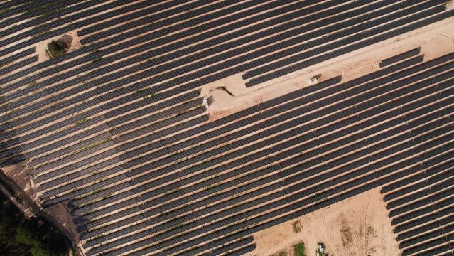 Top-down aerial perspective of symmetrical solar panel rows during the construction phase of a new solar energy plant.