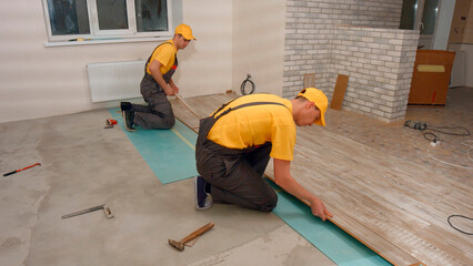 Laying floorboard. Team of builders make renovation of apartment. Laying parquet.