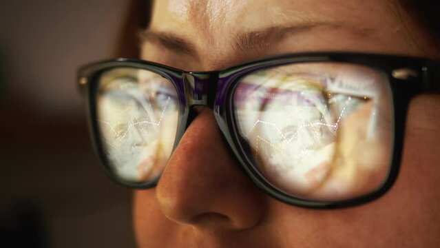In the reflection of glasses on a female face, surfing the Internet and making money with growing graphs and the movement of fiat dollars. Inflation and rising prices. Cash. Cg