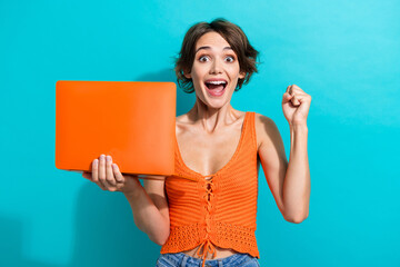 Portrait of overjoyed girl wear orange knit top holding laptop win betting scream yes clenching...