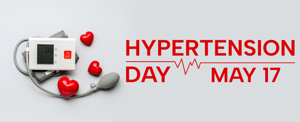 Electronic sphygmomanometer and red hearts on light background