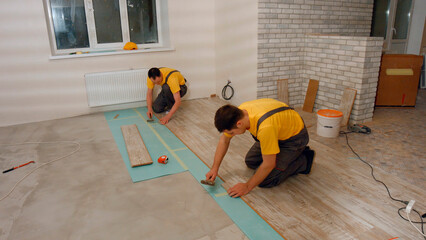 Workers lay the floor in the house. Laying laminate.