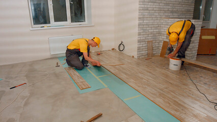 Laying floorboard. Team of builders make renovation of apartment. Laying parquet.