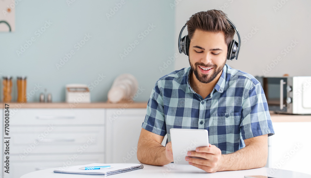 Wall mural young man using tablet computer for online learning at home